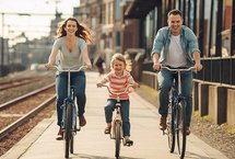Kobieta, dziecko i mężczyzna na rowerach.