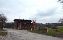 Przystanek Cieśle. Widok na przejazd kolejowy z krzyżem św. Andrzeja i znakiem STOP, a także budynek kolejowy z nazwą stacji. Fot. M. Pabiańska.