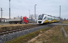 Pociąg pasażerski Kolei Dolnośląskich jedzie po torze, w oddali samochód ciężarowy fot. Radosław Śledziński
