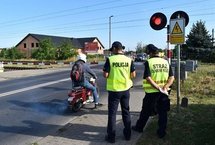 Policjant z sokistą przy zamkniętym szlabanie, kierowca skutera.