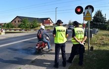 Policjant z sokistą przy zamkniętym szlabanie, kierowca skutera.