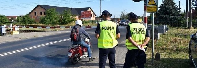 Policjant z sokistą przy zamkniętym szlabanie, kierowca skutera.
