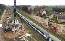 Wykonawcy na budowie wiaduktu nad torami w Ciechanowie. Widać przejeżdżający pociąg i dźwig montujący konstrukcję obiektu, fot. Grzegorz Biega (2)