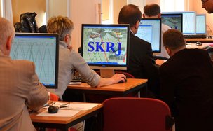 Widok na kilka osób siedzących tyłem przy stanowiskach komputerowych. Na ekranach widoczna aplikacja SKRJ