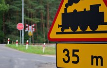 Znak drogowy informujący o przejeździe za 35 m, w tle przejazd.