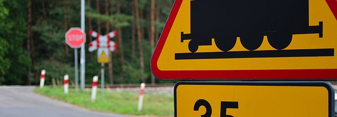 Znak drogowy informujący o przejeździe za 35 m, w tle przejazd.