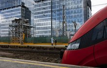 Pociąg stojący przy peronie, w tle podróżni na peronie, filar, budowanie kładki, dalej szklane budynki_Warszawa Zachodnia, fot. Izabela Miernikiewicz