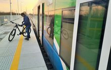 Stacja Chorzelów - na peronie podróżny z rowerem, obok stoi pociąg, fot. Dominik Konarek