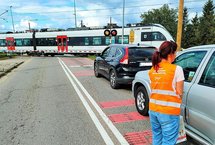 Koordynator kampanii podczas akcji ulotkowej, przejazd kolejowy, pociąg na torach