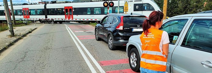 Koordynator kampanii podczas akcji ulotkowej, przejazd kolejowy, pociąg na torach