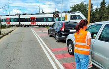 Koordynator kampanii podczas akcji ulotkowej, przejazd kolejowy, pociąg na torach