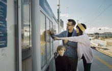 Pasażerowie przy gablocie z rozkładem jazdy. Źródło PKP Polskie Linie Kolejowe S.A.