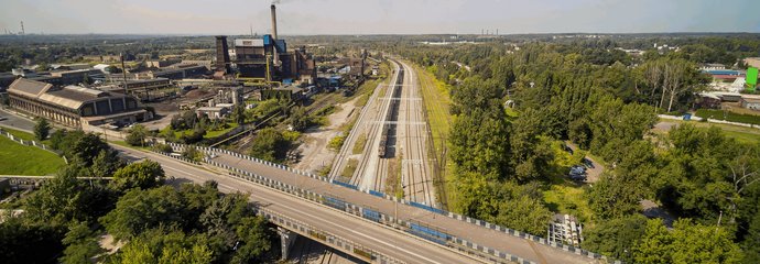 Pociąg towarowy jedzie po nowym torze w okolicach stacji Bytom Bobrek, widać wiadukt drogowy i tereny przemysłowe, fot. Szymon Grochowski