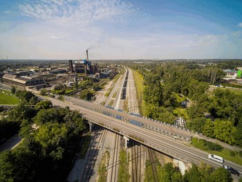 Pociąg towarowy jedzie po nowym torze w okolicach stacji Bytom Bobrek, widać wiadukt drogowy i tereny przemysłowe, fot. Szymon Grochowski