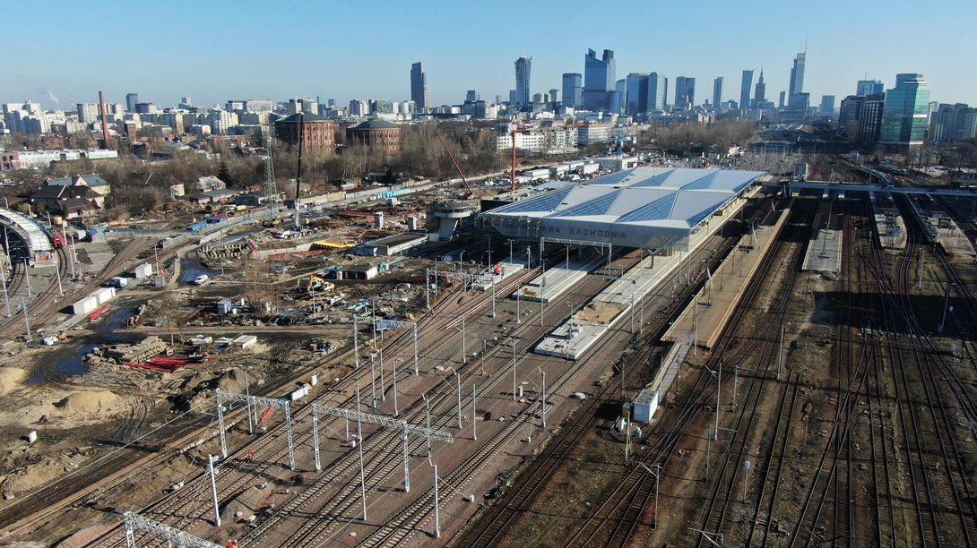 Widok z góry na stację Warszawa Zachodnia. Tory, bramkni sieci trakcyjnej, perony. Widoczna hala peronowa. w tle centrum Warszawy, fot. Andrzej Lewandowski