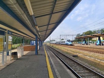 Stacja Tychy, pociąg wjeżdża na peron, pod wiatą tablica informacyjna, fot. Katarzyna Głowacka