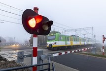 Pociąg na przejeździe, zamknięte rogatki, pulsujące światło