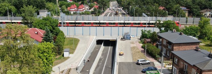 Widok z góry na nowy tunel pod torami w Legionowie, widać tory, przejeżdzający pociąg i nowe drogi dojazdu do tunelu, fot. P. Mieszkowski