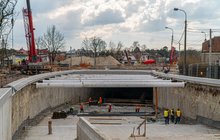 Wykonawcy i maszyny na budowie tunelu kolejowo-drogowego, Sulejówku, widać przejeżdżający pociąg, fot. Artur Banach