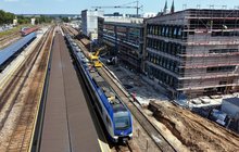 Pociąg przejeżdża obok budowanego peronu na stacji Kielce, w tle budynek dworca, widok z lotu ptaka, fot. Piotr Hamarnik
