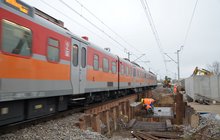 Pociąg przejeżadża po konstrukcji odciążającej. Obok robotnicy budują docelową obudowę przejścia podziemnego. Fot. M. Pabiańska 11.24