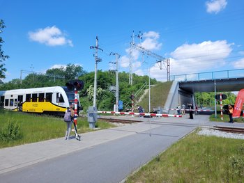 Skrzyżowanie kolejowo-drogowe we Wrocławiu, widać przechodniów i przejeżdżający pociąg, fot. Mirosław Siemieniec