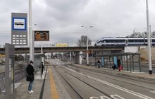 Przebudowany wiadukt kolejowy nad ul. Długą we Wrocławiu; na zdjęciu nowe konstrukcje wiaduktu; pod wiaduktem przystanek tramwajowy, na wiadukcie pociąg pasażerski 