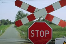 Krzyż św. Andrzeja, znak STOP, w tle przejazd i droga