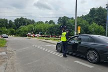 Sokista wręcza ulotkę kierowcy oczekującemu przed zamkniętym szlabanem