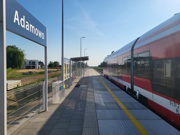 Pociąg przy nowym przystanku Adamowo, po lewej tablica z nazwą przystanku; fot. Radek Śledziński