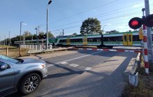 Przejazd kolejowo-drogowy w Sulejówku, samochód czeka przed rogatkami, w tle jadący pociąg. Fot. Rafał Wilgusiak