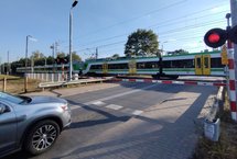 Przejazd kolejowo-drogowy w Sulejówku, samochód czeka przed rogatkami, w tle jadący pociąg. Fot. Rafał Wilgusiak