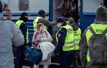 Funkcjonariuszka Straży Ochrony Kolei rozmawia z pasażerką – uchodźczynią z Ukrainy na peronie. W tle pozostali funkcjonariusze pomagają podróżnym wysiąść z ewakuacyjnego pociągu. Fot. Tomasz Jaskot