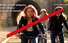 Przekreśleni rowerzyści jadący po torach na tle tunelu