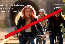 Przekreśleni rowerzyści jadący po torach na tle tunelu