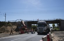 cieżarówka przejeźdżająca nad wiaduktem kolejowym w przebudowie na trasie CMK, w tele maszyna i pracownicy, fot. Izabela Miernikiewicz