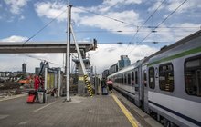 Pociąg stojący przy peronie, podróżni i kładka nad peronem w tle, fot. Izabela Miernikiewicz