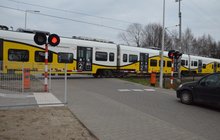 Przez przejazd na ul. Przy Torze we Wrocławiu zbliża się pociąg Kolei Dolnośląskich. Przed opuszczonymi rogatkami przed przejazdem stoi samochód osobowy. Fot. M. Pabiańska