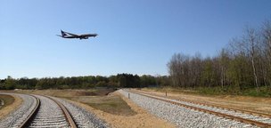 Samolot lecący nad nowymi torami kolejowymi.