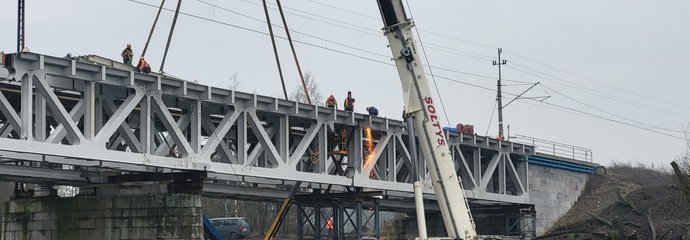 Dźwig przy budowie nowego przęsła mostu nad Wartą w Obornikach, widoczna rzeka, ceglane przęsło, a na góze sieć trakcyjna_fot.Radek Śledziński