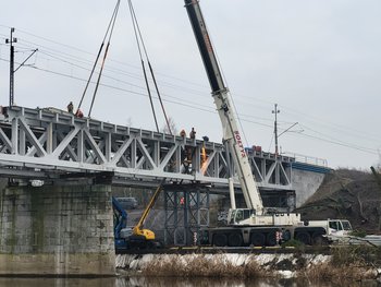 Dźwig przy budowie nowego przęsła mostu nad Wartą w Obornikach, widoczna rzeka, ceglane przęsło, a na góze sieć trakcyjna_fot.Radek Śledziński