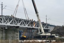 Dźwig przy budowie nowego przęsła mostu nad Wartą w Obornikach, widoczna rzeka, ceglane przęsło, a na góze sieć trakcyjna_fot.Radek Śledziński