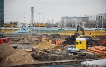 Widok na plac budowy na stacji Warszawa Zachodnia, pracownicy wykorzystują maszyny, w tle pociąg, fot. PLK