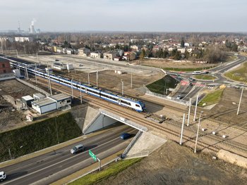 Dąbrowa Górnicza, po wiadukcie kolejowym jedzie pociąg, pod obiektem samochody, widok z lotu ptaka, fot. Grzegorz Biega