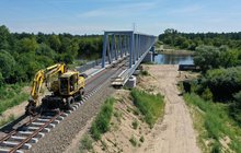 Prace budowlane odbywające się na moście kolejowym nad Narwią. Po moście porusza się koparka, fot. Szymon Grochowski