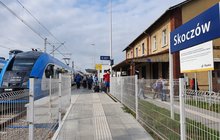 Stacja Skoczów, tablica z nazwą stacji, w tle pociąg i podróżni, fot. Katarzyna Głowacka