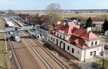 Widok z góry na stację Modlin, widać tory, kładkę dla pieszych oraz budynek dworca, fot. P. Mieszkowski