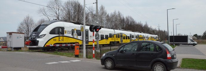 Do przejazdu na ul. Przy Torze we Wrocławiu zbliża się pociąg Kolei Dolnośląskich. Przed opuszczonymi rogatkami przed przejazdem stoi samochód osobowy. Fot2. M. Pabiańska