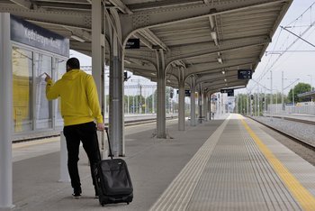 Pasażer stoi przy tablicy z rozkładem jazdy na stacji Kędzierzyn Koźle. Autor. Łukasz Hachuła