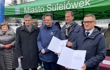 Przedstawiciel wykonawcy i PLK SA prezentują podpisaną umowę na nowy tunel pod torami w Sulejówku, obok przedstawiciele MI i władz samorządowych, fot. Anna Znajewska-Pawluk